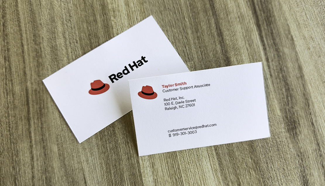 Foto di un biglietto da visita Red Hat in cui il cappello compare di fianco al nome del dipendente.
