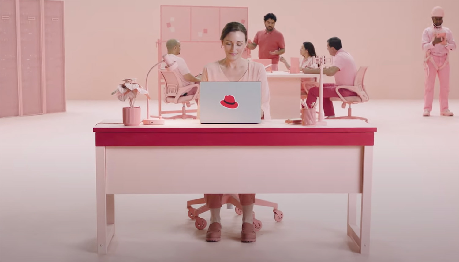 Fotogramma di un video della serie Connected Campaign. Una donna è seduta alla scrivania e il cappello compare sulla scocca del laptop su cui sta lavorando.