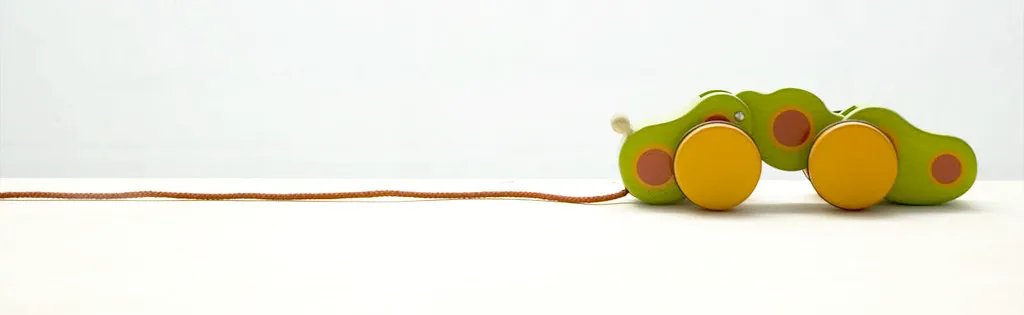 A photograph of a green and yellow wooden toy caterpillar with a red string attached for pulling it along. A photograph of a green and yellow wooden toy caterpillar with a red string attached for pulling it along.